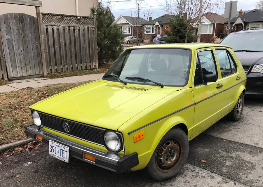 Ярко-желтый MK1 VW Rabbit припаркован у бордюра
